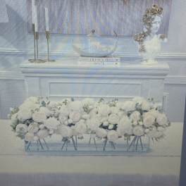 White floral arrangement in a clear rectangular vase on a table