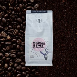 Bag of ground coffee surrounded by coffee beans