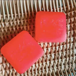 Two coral-red square tins on a woven basket surface.