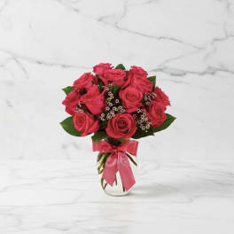 Pink rose bouquet in a clear glass vase with a ribbon