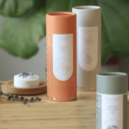 Assorted cylindrical candle tubes on a wooden surface with a small candle dish