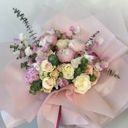Hand-tied bouquet of pink peonies and cream roses wrapped in layered pale pink paper.