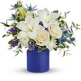 White lilies and roses in a blue vase with purple accents