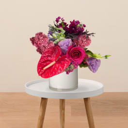 Bright pink and purple bouquet in a white vase