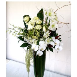 White floral arrangement in a tall green glass vase