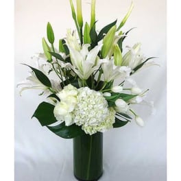 White lilies and hydrangeas arranged in a tall green vase