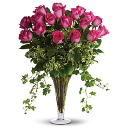 Pink roses arranged in a clear glass vase with trailing greenery