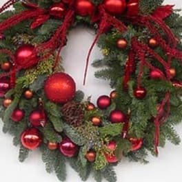 Christmas wreath with red ornaments and ribbon on evergreen foliage
