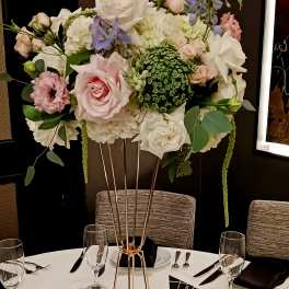 Tall floral centerpiece with pink and white roses on a gold stand