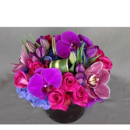 Bouquet of pink roses, purple orchids, and blue hydrangeas in a black vase