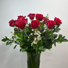 Red roses in a tall glass vase with white filler flowers