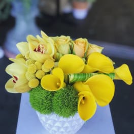 Yellow calla lilies and roses in a white textured vase