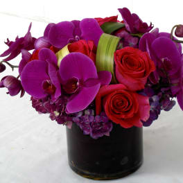 Purple orchids and red roses in a black vase