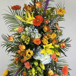 Tall standing floral spray with mixed bright flowers on a black easel
