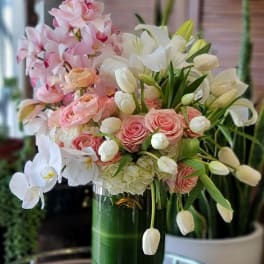 Pink and white floral arrangement in a tall glass vase