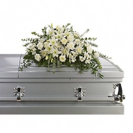 White floral casket spray on a gray casket