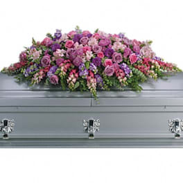 Large pink and purple floral casket spray on a gray casket
