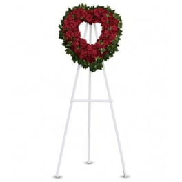Heart-shaped red rose wreath on a white easel stand