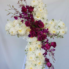 Cross-shaped floral arrangement of white chrysanthemums and magenta roses on a stand
