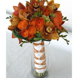 Orange bouquet with orchids and roses in a tall glass vase