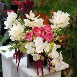 Pink roses and white orchids in a square glass vase