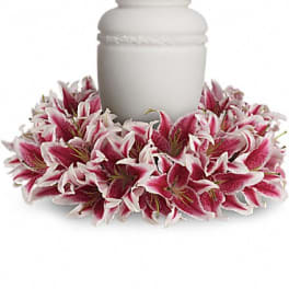 Pink and white lilies arranged around a white urn