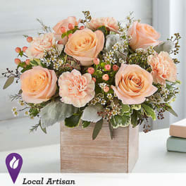 Peach roses and carnations arranged in a wooden box