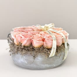 Pink roses arranged in a low silver bowl with ribbon trim