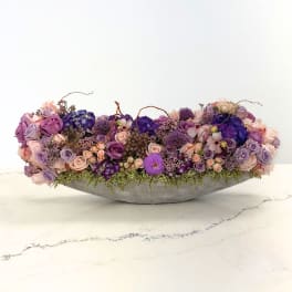 Low floral centerpiece with purple and pink roses in a gray bowl