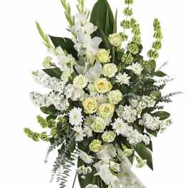 White and pale yellow funeral spray on a black easel
