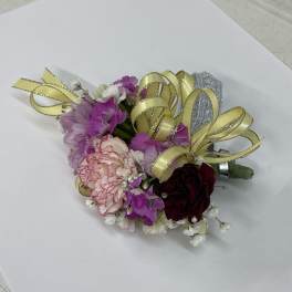 Small corsage with pink and burgundy flowers and gold ribbon loops