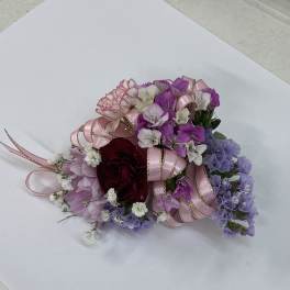 Small bouquet of pink, purple, and white flowers with ribbon accents