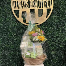 Gift basket with flowers, candles, and a plush toy under clear wrap