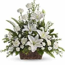 White lilies and carnations arranged in a brown wicker basket