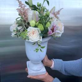 White floral arrangement in a pedestal vase with lilies and roses