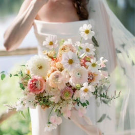 Bride holding a pastel bouquet with white daisies and blush ranunculus