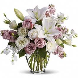 Pink and white bouquet of lilies, roses, and stock in a glass vase