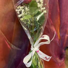 Single pink rose wrapped in clear plastic with baby's breath