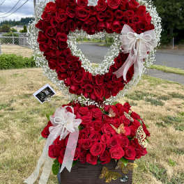 Heart-shaped rose arrangement with white baby's breath and ribbon bows