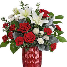 Red roses and white lilies arranged in a red glass vase