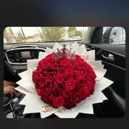 Large bouquet of red roses with a jeweled crown topper and white wrap