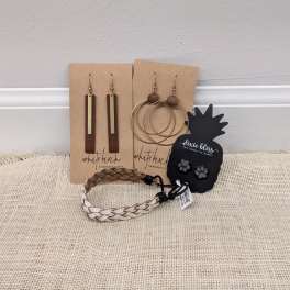 Assorted earrings and braided bracelets displayed on cards and a table