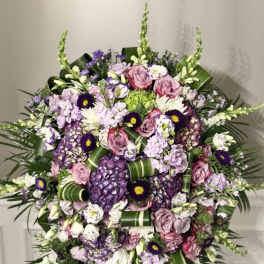 Large standing floral spray with pink and purple flowers on a black easel