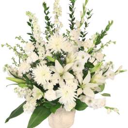 White floral arrangement in a cream vase with lilies and daisy-like blooms