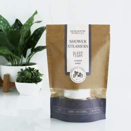 Package of shower steamers beside two potted plants