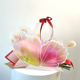 Pink and yellow floral gift bag with a red ribbon bow