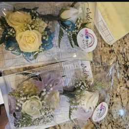 Small rose boutonnieres wrapped in clear plastic with ribbon accents