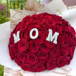 Round bouquet of red roses with pearl letters spelling MOM
