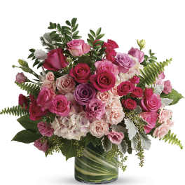 Pink and purple rose bouquet in a green glass vase