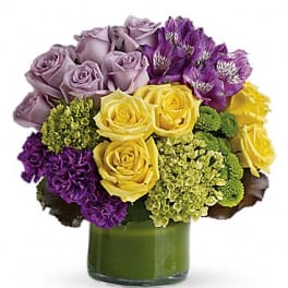 Bouquet of yellow, lavender, and purple flowers in a glass vase
